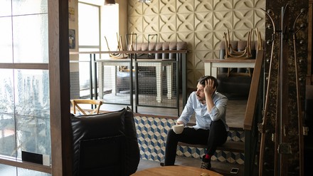 Gastronom sitzt in seinem leeren, geschlossenen Restaurant/Café