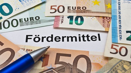 Schriftzug „Fördermittel“ umgeben von Euroscheinen