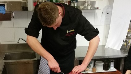 Mann schneidet Fleisch in Küche