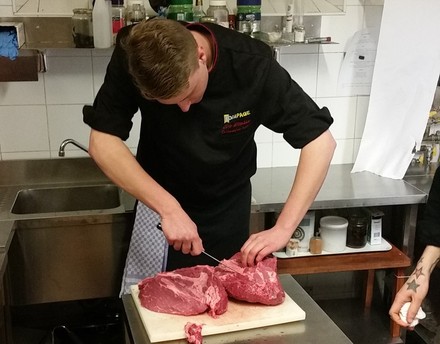 Mann schneidet Fleisch in Küche