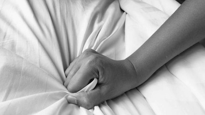 Hand greift in Bettlaken