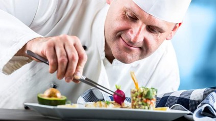 Ein lächelnder Koch bereitet feine Köstlichkeiten zu
