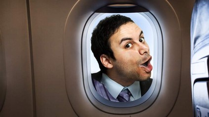 Mann drückt sein Gesicht an ein Flugzeug Bullauge