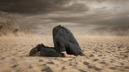 Mann steckt Kopf in den Sand