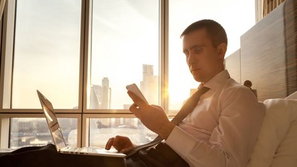 Mann sieht in Hotelzimmer auf sein Smartphone