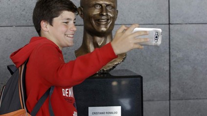 Kind fotografiert sich mit Cristiano Ronaldo Statue