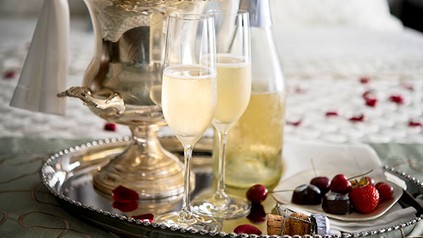 Eine Flasche Schaumwein und zwei Gläser mit Schaumwein auf einem edlen Tablet
