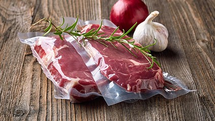 Vakuumiertes Fleisch mit Zwiebeln und einer Stange Rosmarin