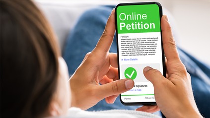 Mann hält Handy in der Hand, auf dem eine Online Petition geöffnet ist