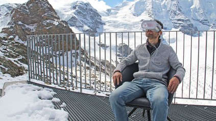 Ein Mann sitzt mit VR-Brille in verschneiten Bergen