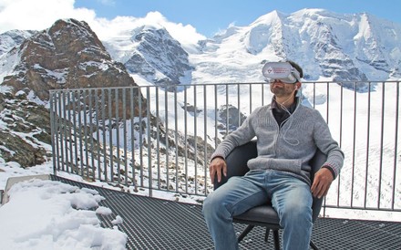 Ein Mann sitzt mit VR-Brille in verschneiten Bergen