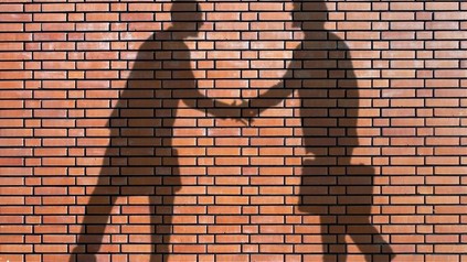 Schatten an Wand: Geschäftsmänner, die sich die Hand geben
