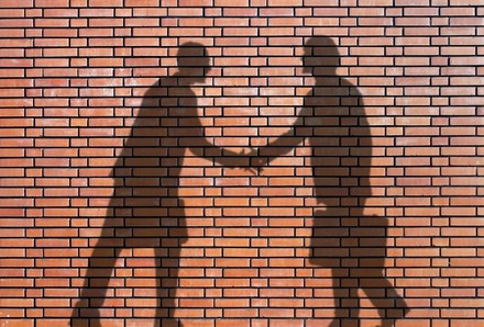 Schatten an Wand: Geschäftsmänner, die sich die Hand geben