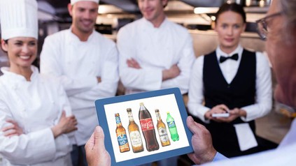 Ein Gastronom mit einem Tablet in der Hand auf dem diverse Getränke zu sehen sind
