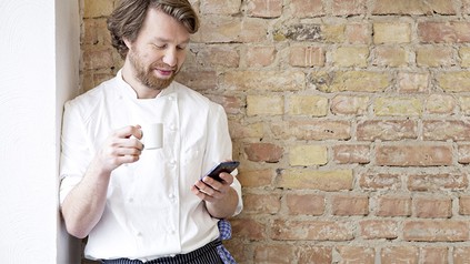 Ein entspannter Koch mit einem Smartphone in der Hand