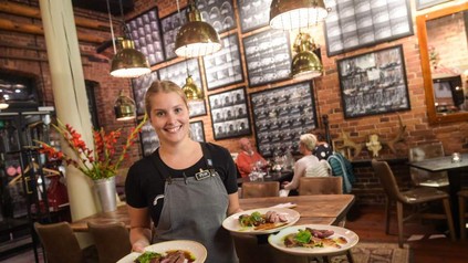 Eine lächelnde Kellnerin mit finnischen Gerichten auf Tellern
