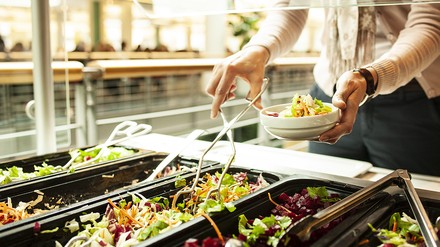 Eine Frau bedient sich an einem Salatbüfett