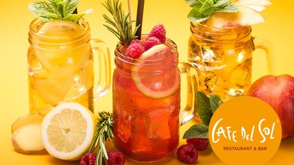 Drei bunte Getränke auf einem Tisch mit frischem Obst und dem Logo von Cafe del sol