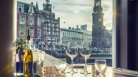 Ein Restauranttisch am Fenster, von dem aus man einen Blick auf den Münzturm in Amsterdam hat