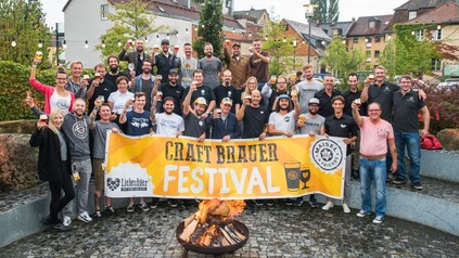 Eine Gruppe fröhlicher Menschen mit einem Banner des Craft Brauer Festivals