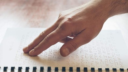 Mann liest Text in Blindenschrift