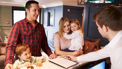 Familie bim Check-in an der Hotelrezeption