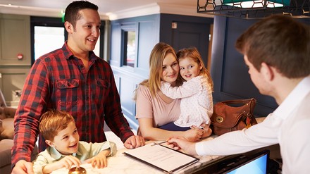 Familie bim Check-in an der Hotelrezeption
