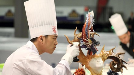 Asiatischer Koch oder Foodartist arbeitet konzentriert an einem Ausstellungsobjekt