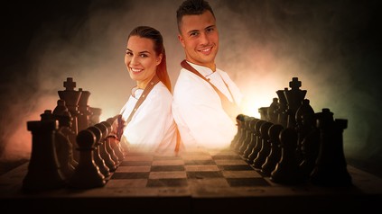 Ein Schachbrett und zwei Hotelmitarbeiter im Hintergrund