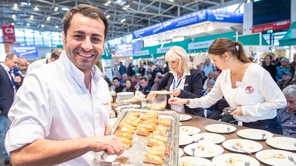 Spitzenkoch Ali Güngörmüs an einem Messestand