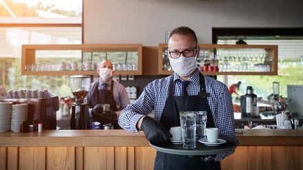 Servicekraft mit Maske und vollem Tablet