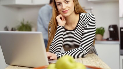 Frau sitzt mit Laptop am Esstisch
