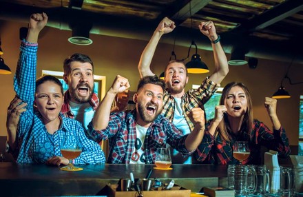 Junge Menschen jubeln in einer Kneipe