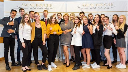 Eine Gruppe junger Lehrlinge vor einem Amuse-Bouche Plakat