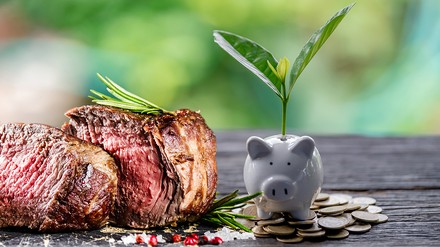 Ein Steak neben einem Sparschwein