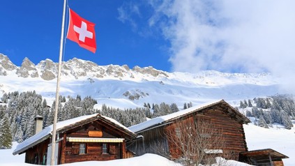 Verschneite Hütte in den Bergen mit Schweizer Flagge