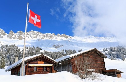 Verschneite Hütte in den Bergen mit Schweizer Flagge