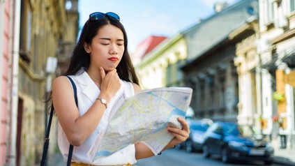 Nachdenkliche asiatische Touristin blickt auf eine Landkarte