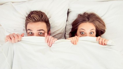 Mann und Frau sehen über Bettdecke