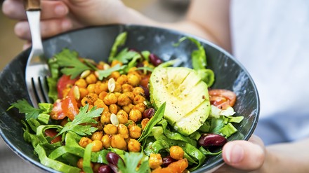 Junge Frau isst einen veganen Salat mit Gemüse und Kichererbsen