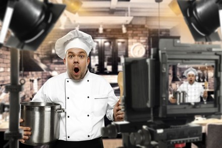 Koch macht erstauntes Gesicht und hält Kochtopf in der Hand