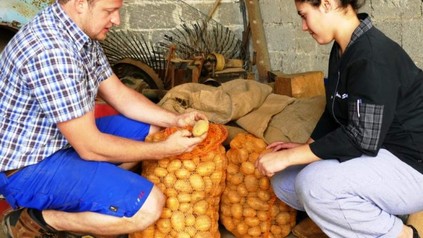 Uwe Steiniger und ein junges Mädchen öffnen zwei Säcke Kartoffeln