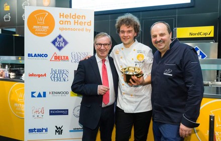 Marianus von Hörsten mit Johann Lafer und einem weiteren Würdenträger hält einen goldenen Topf in der Hand