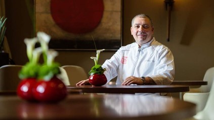 Sternekoch Christian Bau sitzt lächelnd an einem Tisch