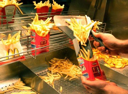Eine Hand, die McDonald’s-Pommes ein tütet. Origineller Rollentausch: Am Ray-Kroc-Tag stehen die Büros leer, da alle Verwaltungskräfte im Restaurant mitarbeiten müssen.