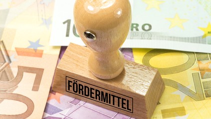 Stempel mit der Aufschrift "Fördermittel" steht auf Euroscheinen