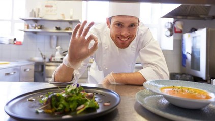 Ein Koch, der in seiner Küche steht und sich freut