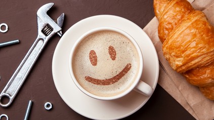 Eine Tasse Kaffee auf einem Tisch, neben der ein Schraubenschlüssel liegt