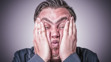 Mann presst sich Hände auf sein Gesicht