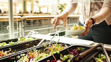 Nahaufnahme einer Frau, die sich an einem Salatbüfett bedient